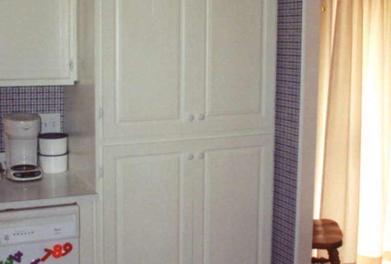 Built-in kitchen pantry, doors closed, provides space.